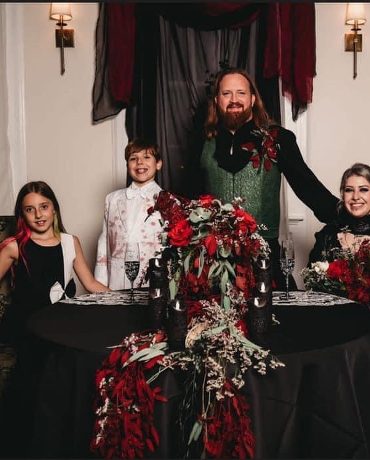 Family portrait with dramatic red floral centerpiece at reception table
